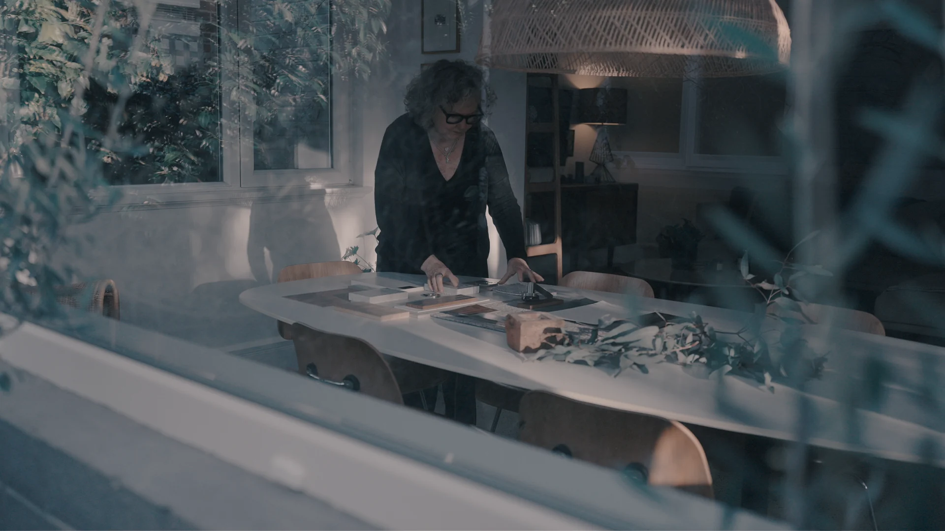 Charlotte Kennedy arranging the Sable material palette, seen through the garden window